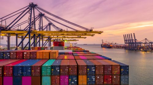 Container ship loading and unloading in deep sea port at sunset,